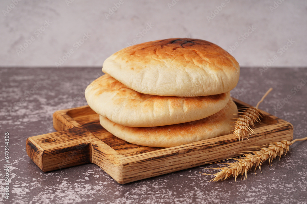 Wooden board of tasty pita bread on table