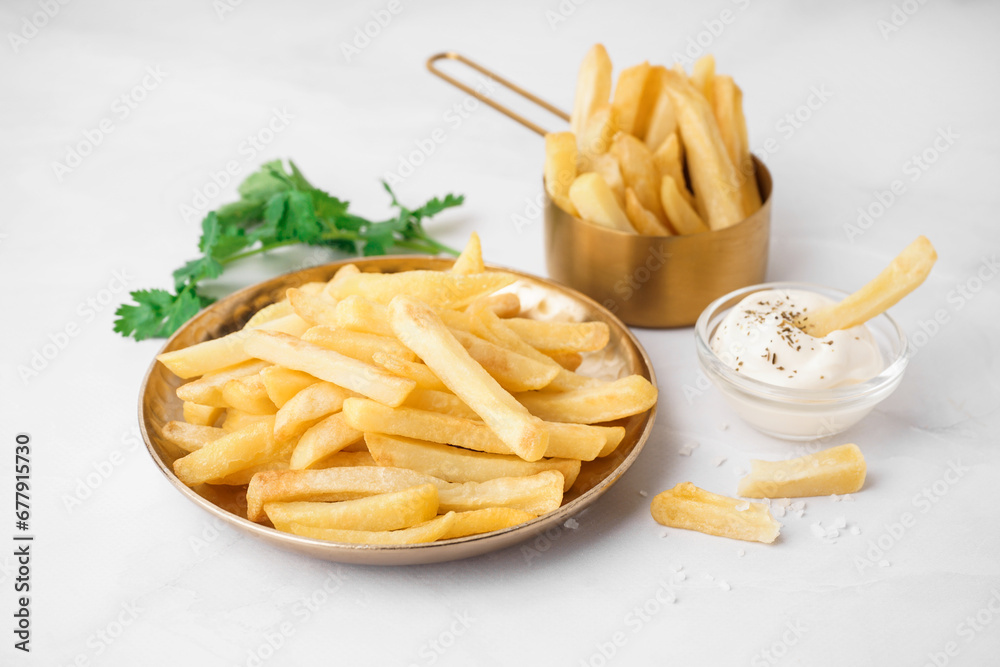 Plate of tasty french fries with sauce on white background