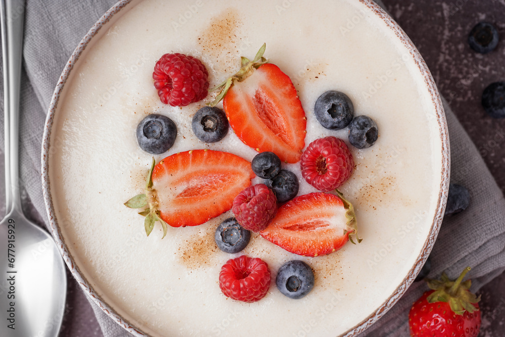 Bowl of tasty semolina porridge with fresh berries on grey background