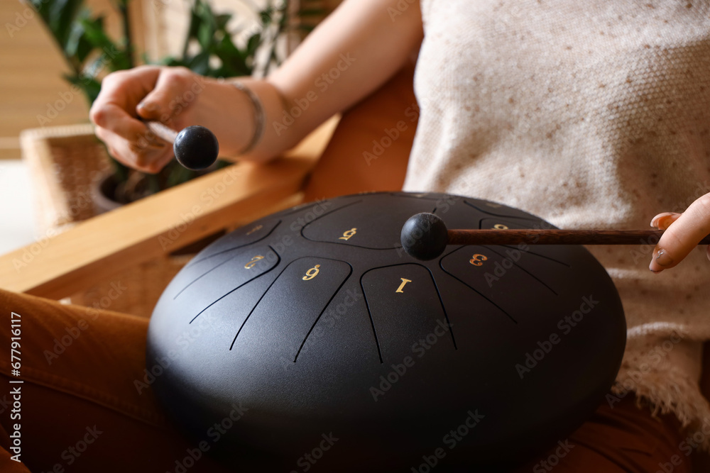 Young woman with sticks playing glucophone in armchair at home, closeup