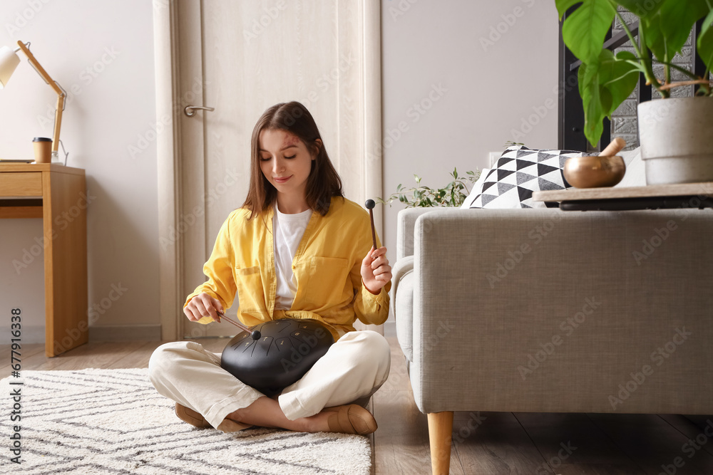 Young woman with sticks playing glucophone at home