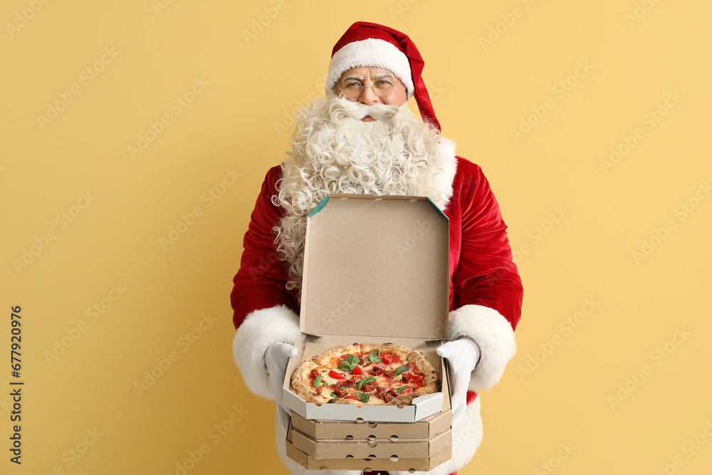 Santa Claus with boxes of tasty pizza on yellow background