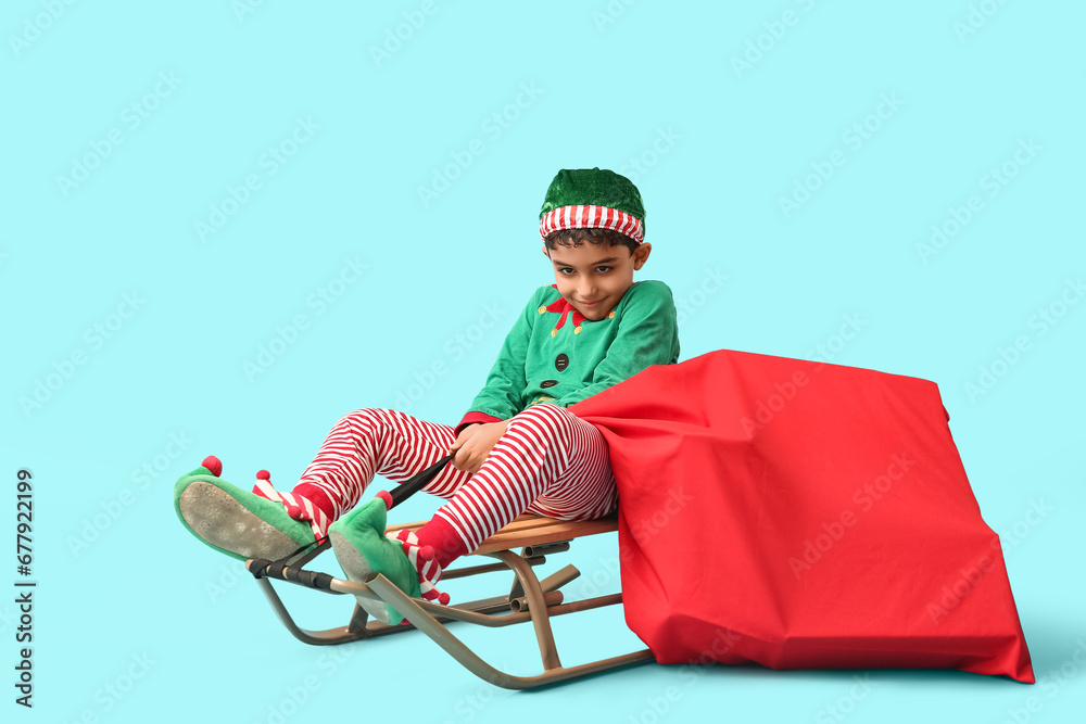 Cute little elf with sled and bag of gifts on blue background