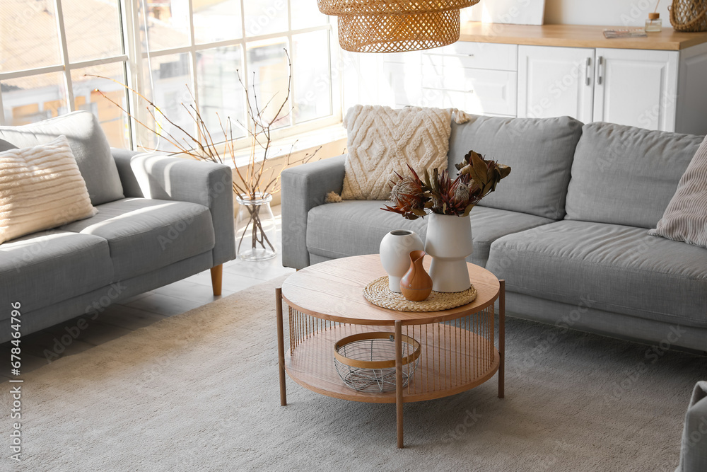 Cozy grey sofas and coffee table with bouquet of dried protea flowers in living room