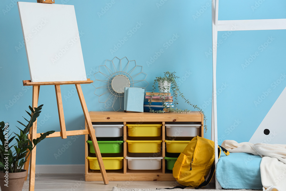 Interior of childrens bedroom with cozy bed, shelving unit and easel