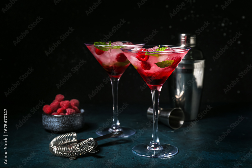 Glasses of fresh raspberry mojito and bowl with berries on blue table