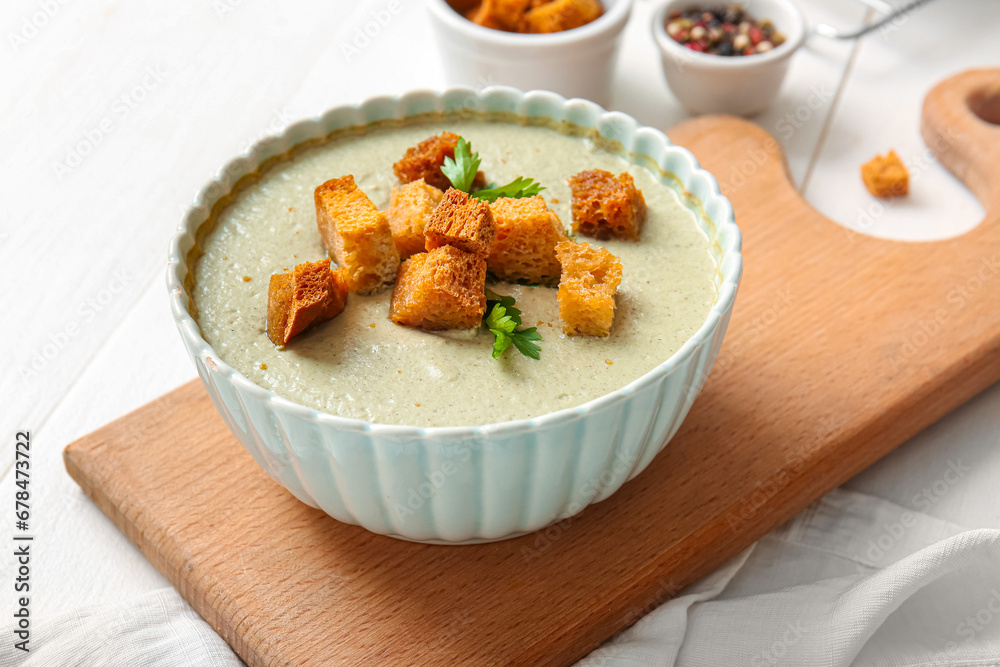 Bowl of tasty cream soup with croutons on white wooden background