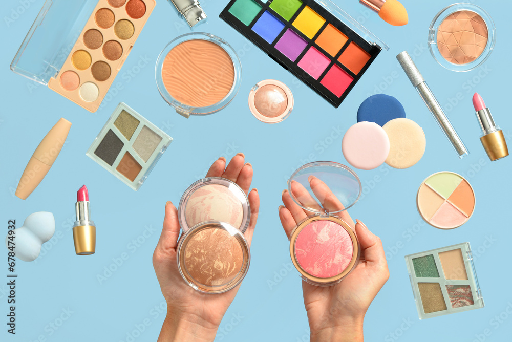 Female hands with different decorative cosmetics on blue background