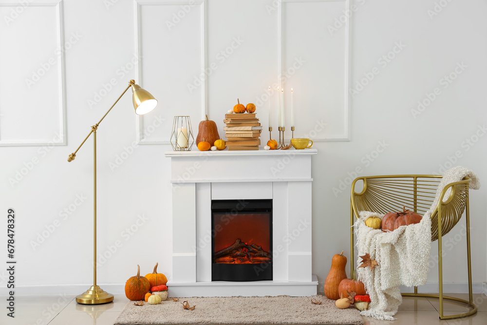 Autumn interior of living room with fireplace, stylish armchair and pumpkins