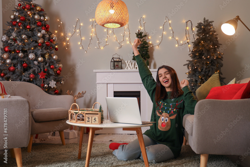 Happy young woman with laptop shopping online for Christmas at home