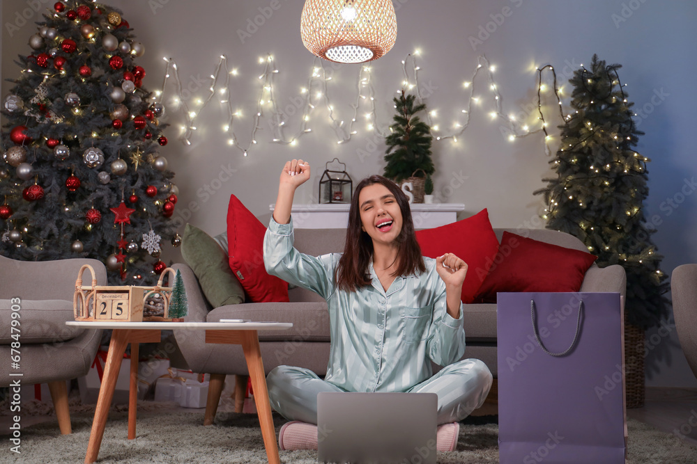 Happy young woman with laptop shopping online for Christmas at home