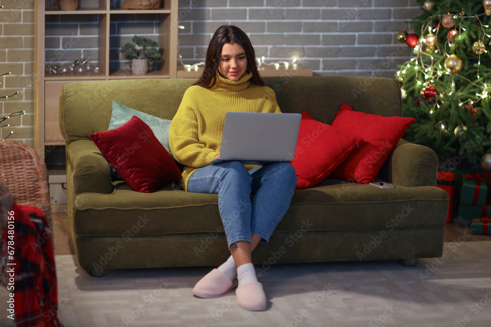 Young woman with laptop shopping online for Christmas at home