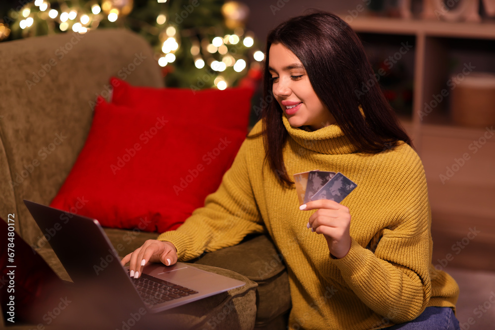 Young woman with credit cards and laptop shopping online for Christmas at home