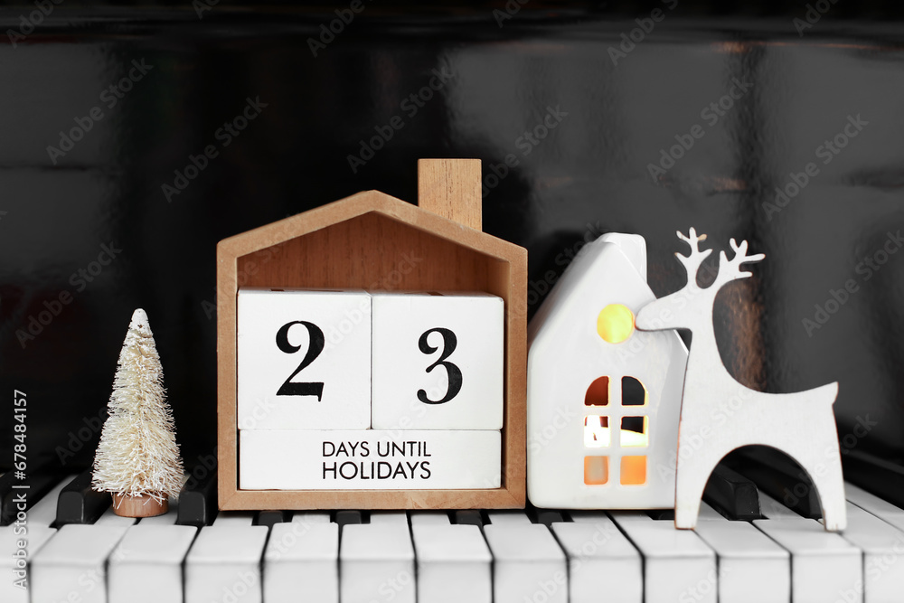 Calendar with text 23 DAYS UNTIL HOLIDAYS and Christmas decorations on piano keys