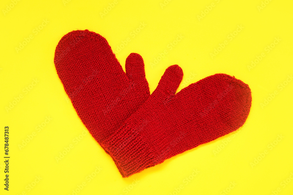 Stylish warm mittens on yellow background