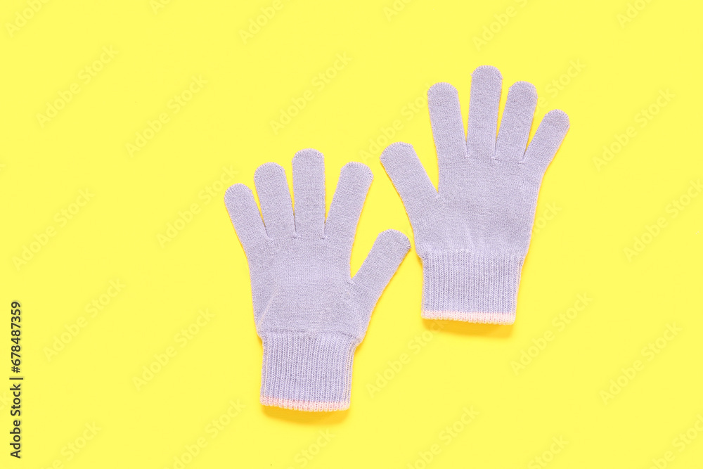 Pair of warm gloves on yellow background