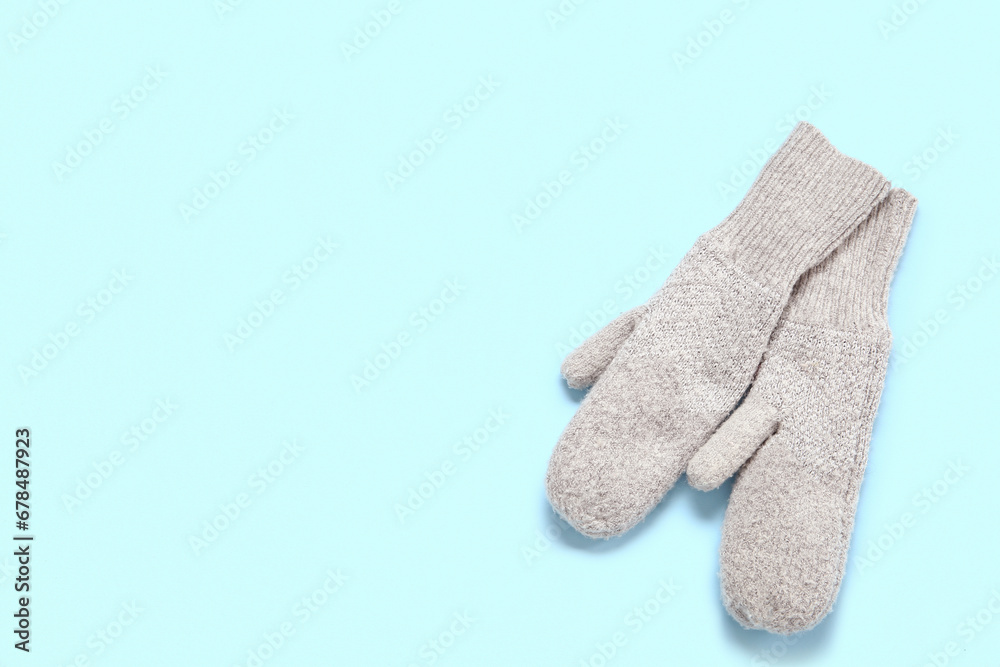 Pair of stylish warm mittens on color background