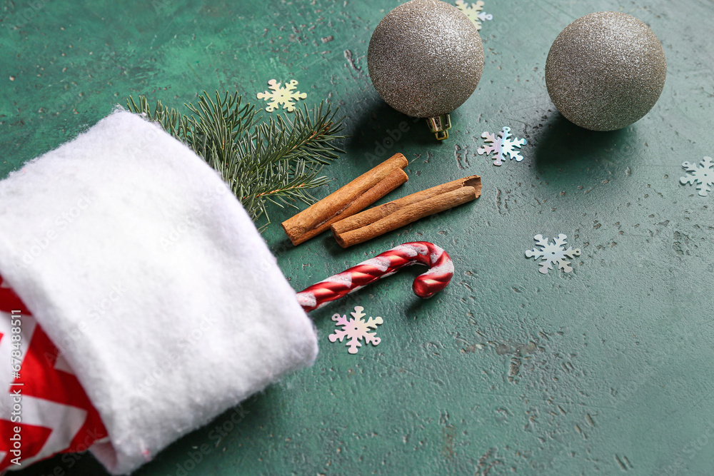 Christmas sock with fir branch, beautiful decorations and cinnamon on green background