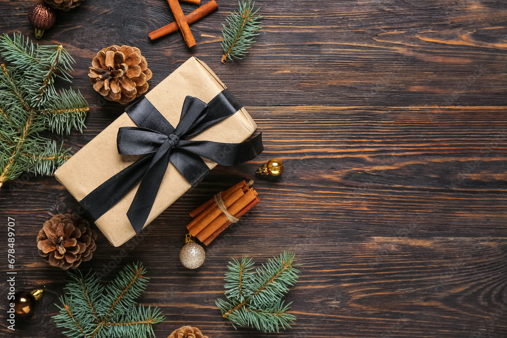 Pine cones with Christmas gift box, fir branches and cinnamon on wooden background