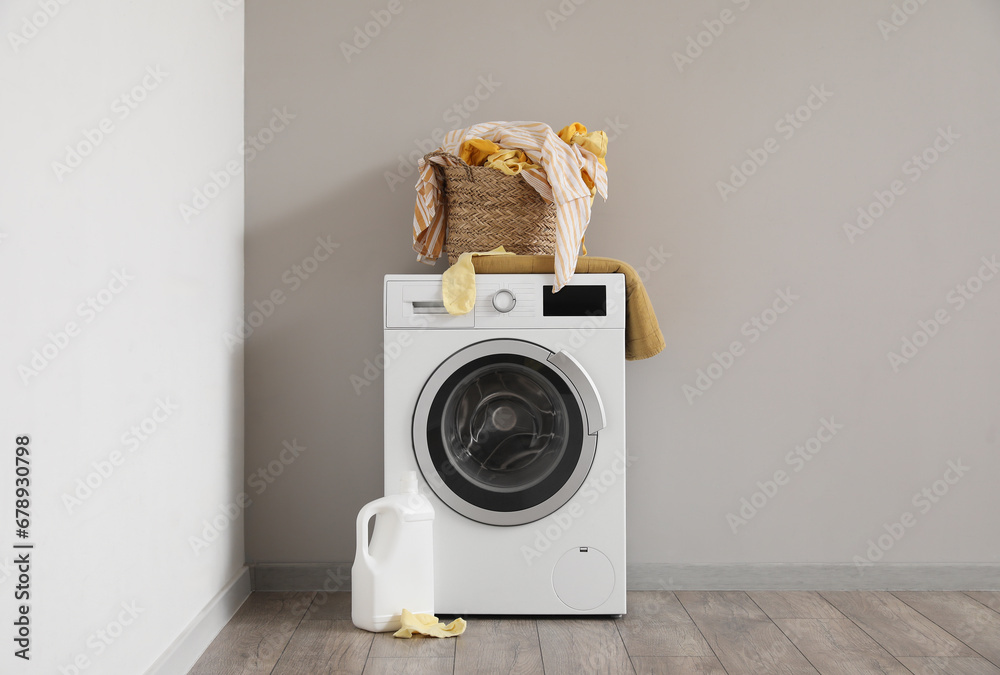 Basket with dirty clothes on washing machine in laundry room