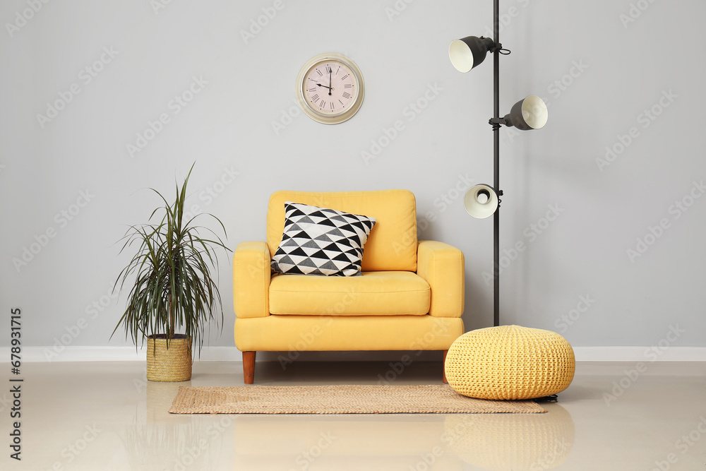 Yellow armchair with cushion and standard lamp near white wall