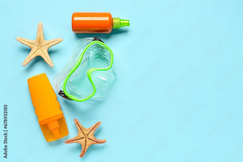 Snorkeling mask, bottles of cosmetic products and starfishes on color background