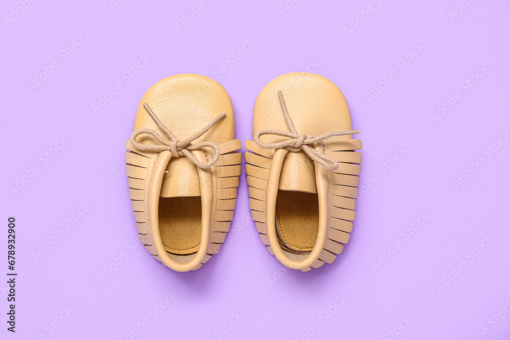 Pair of stylish baby booties on lilac background