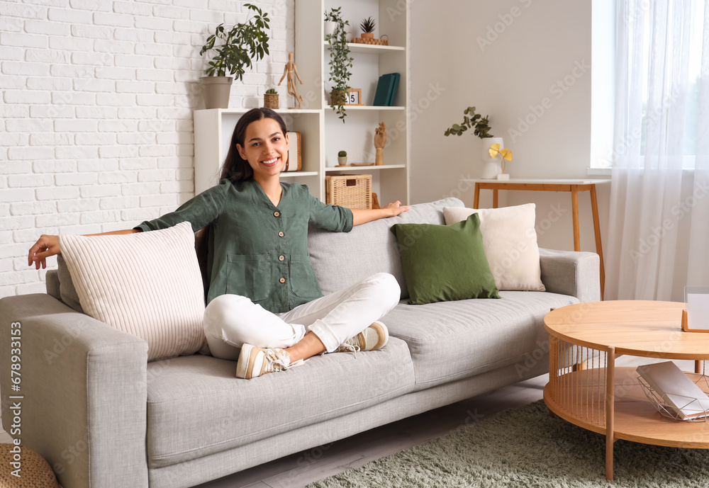 Beautiful happy young woman relaxing on sofa in living room