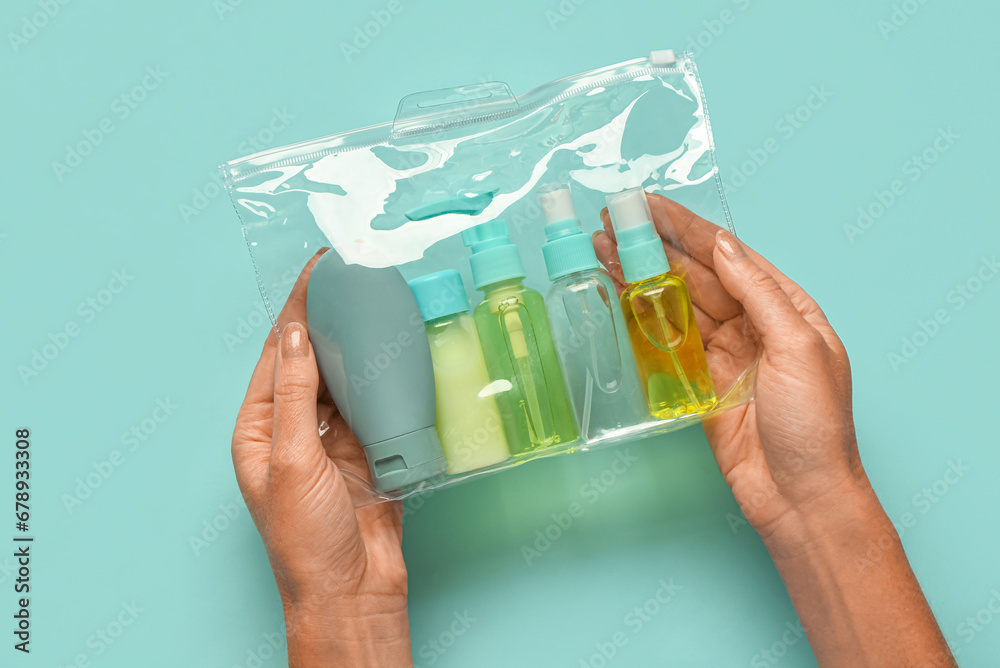 Woman holding set of travel cosmetic products on color background, closeup