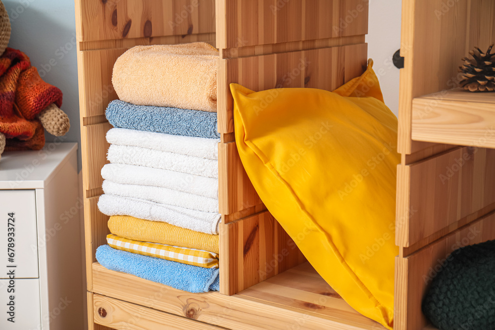 wooden shelving unit with stack of clean towels and pillow, closeup