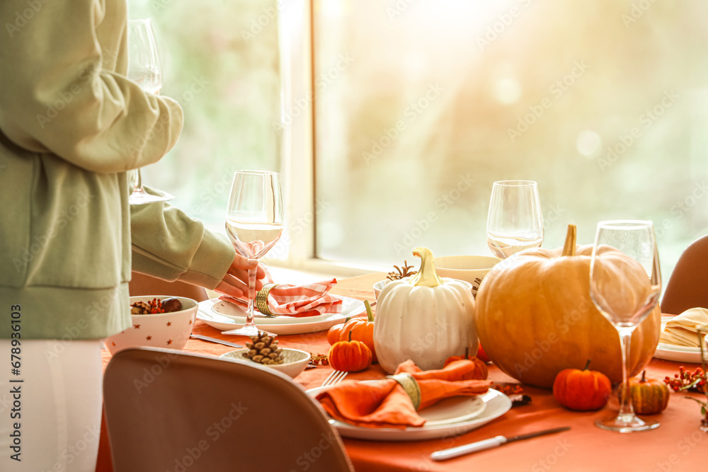 Woman decorating table for Thanksgiving dinner in modern dining room, closeup