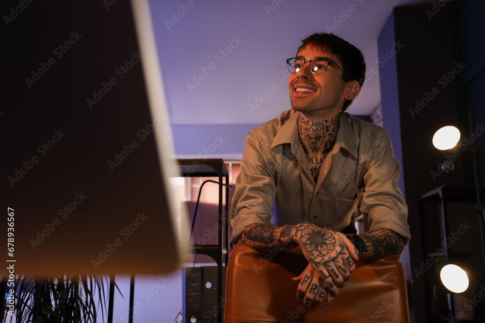 Young tattooed man working in office at night