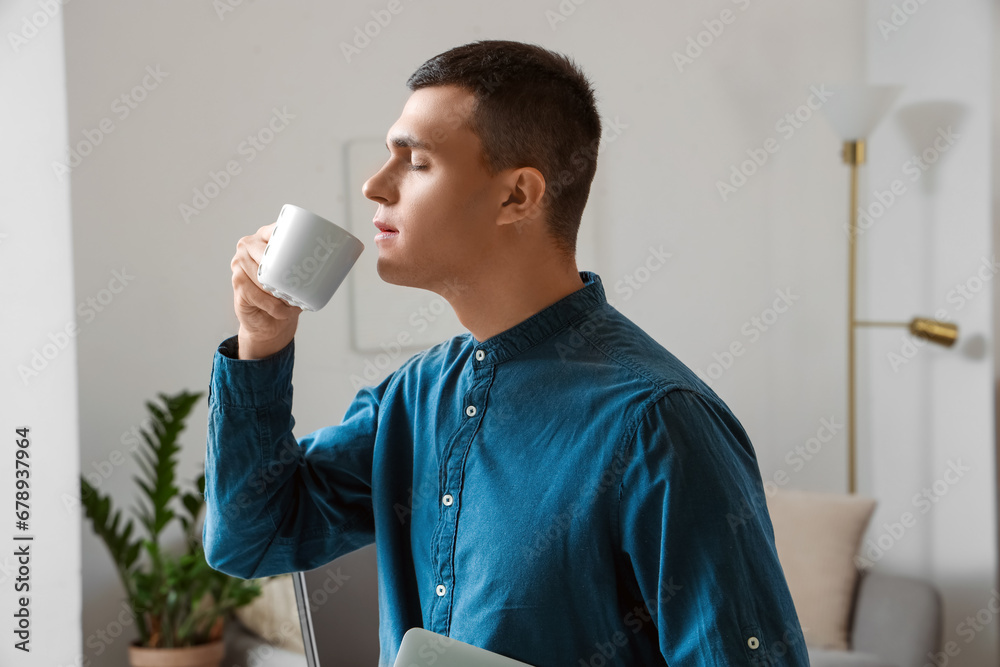 Handsome young man drinking coffee at home, closeup