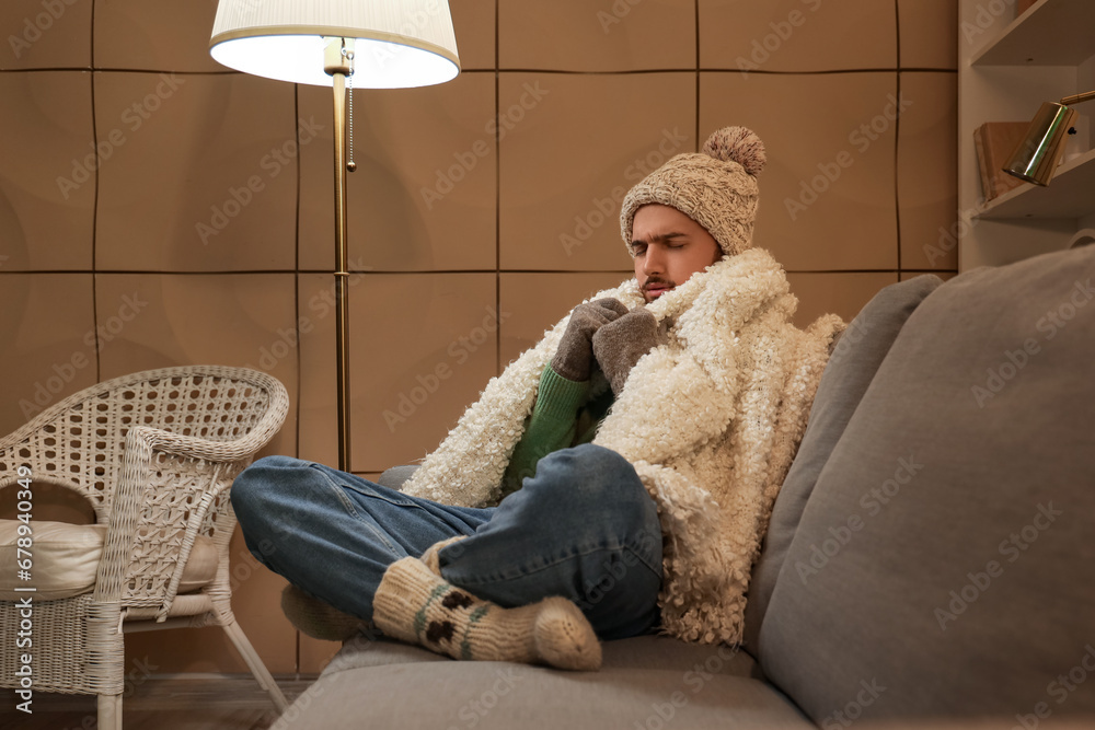 Frozen young man with warm plaid at home in evening