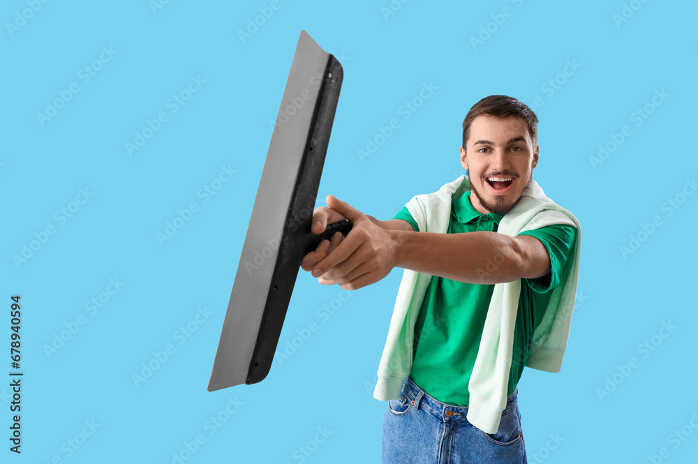 Young man with trowel on blue background