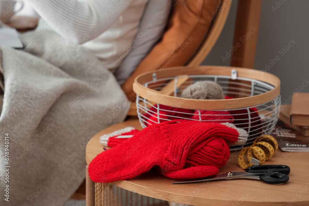 Knitted socks with yarn on table in room, closeup