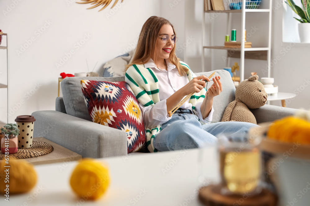 Young woman knitting with needles at home