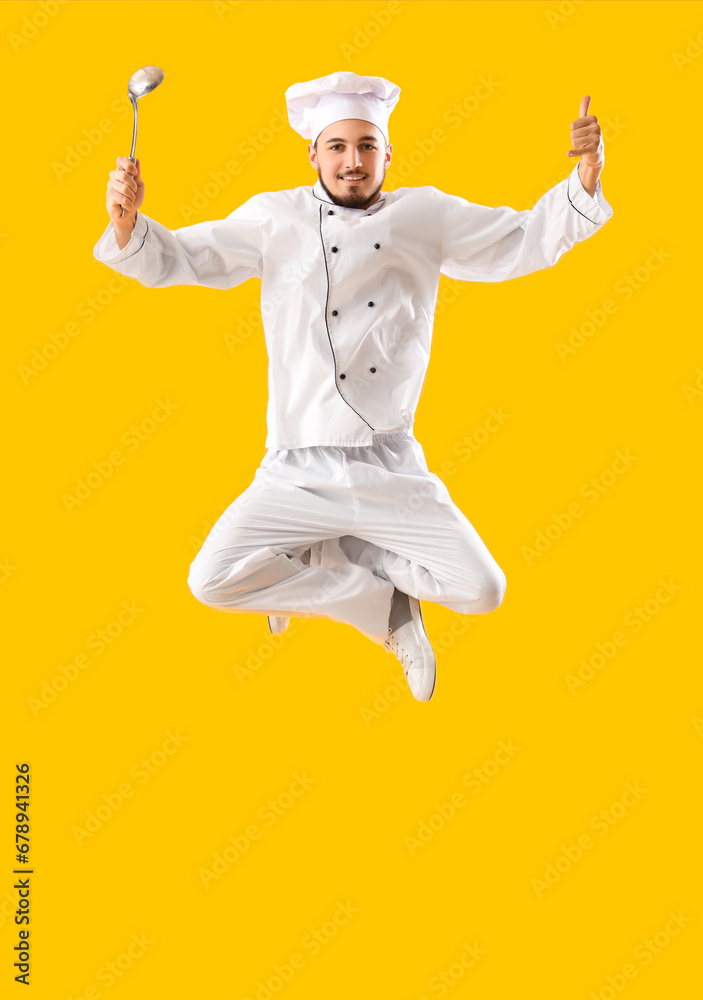 Jumping male chef with ladle showing  call me  gesture on yellow background