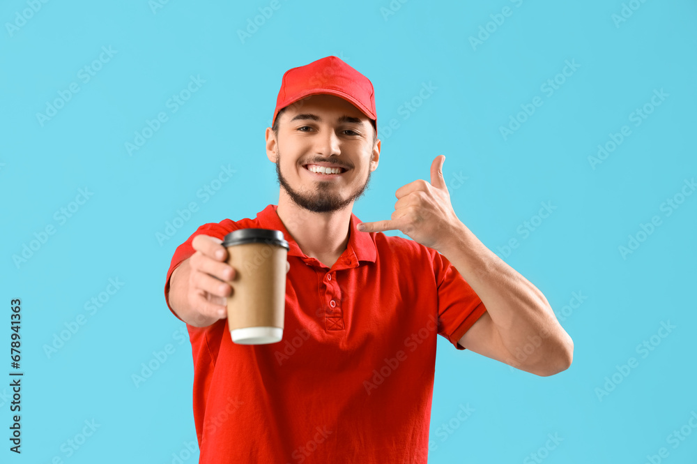 Male courier with coffee cup showing  call me  gesture on blue background