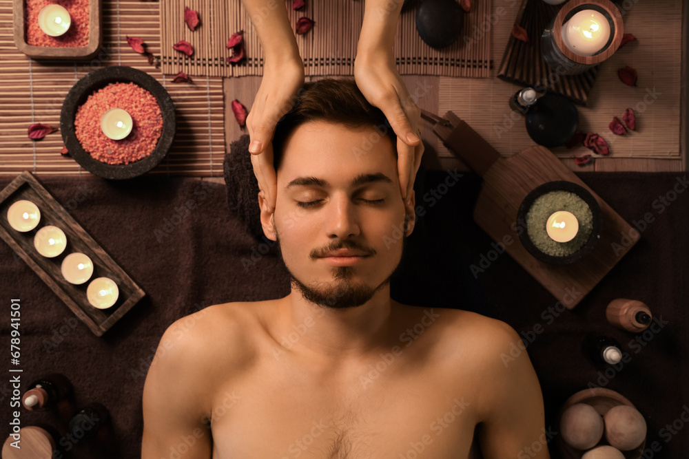 Young man getting massage in dark spa salon, top view