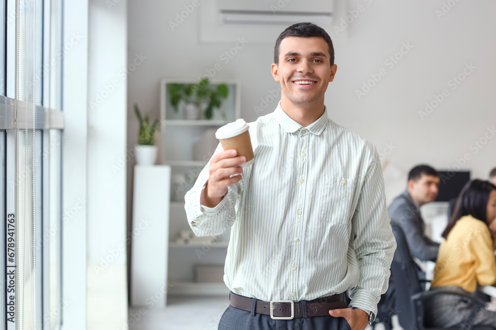 Young businessman with coffee cup in office