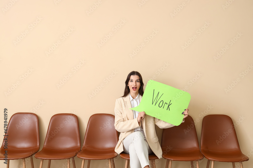 Businesswoman holding speech bubble with word WORK near beige wall