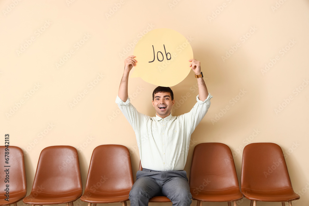 Businessman holding speech bubble with word JOB near beige wall