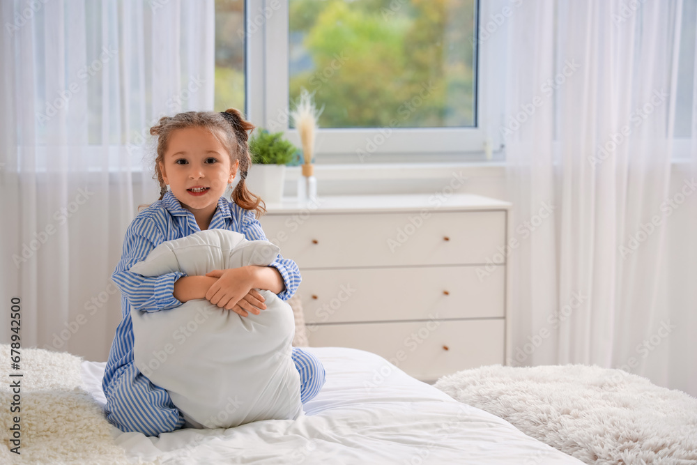 Cute little girl with pillow in bedroom