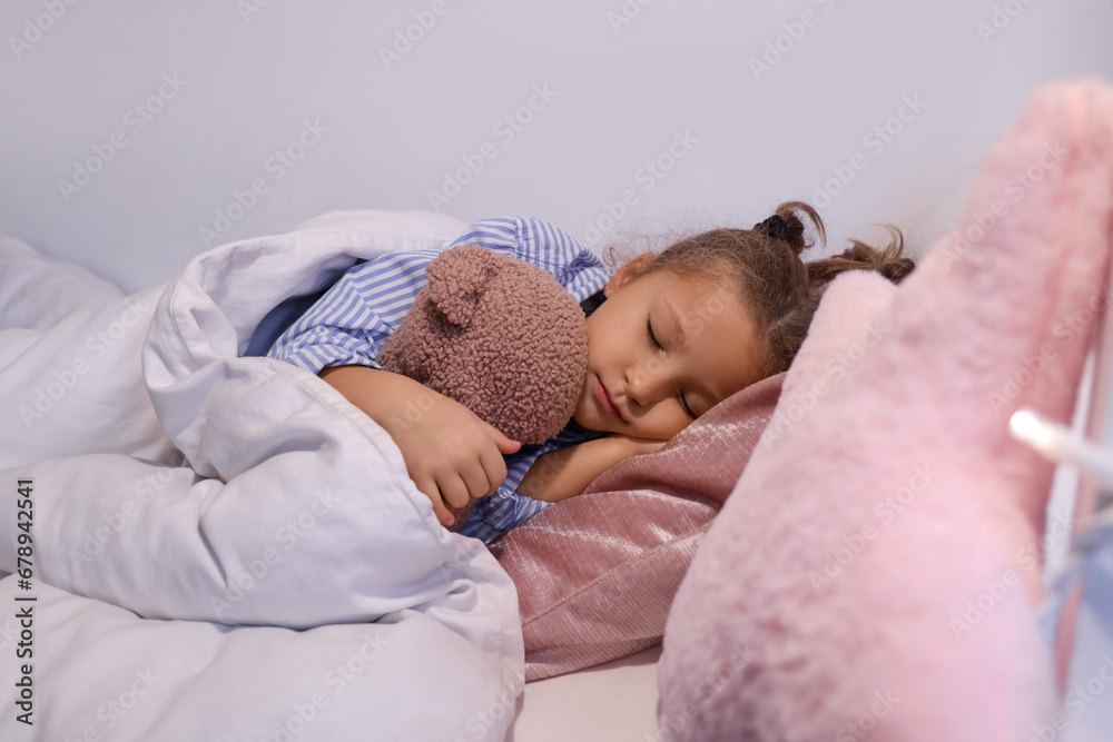 Cute little girl with toy bear sleeping in bedroom at night