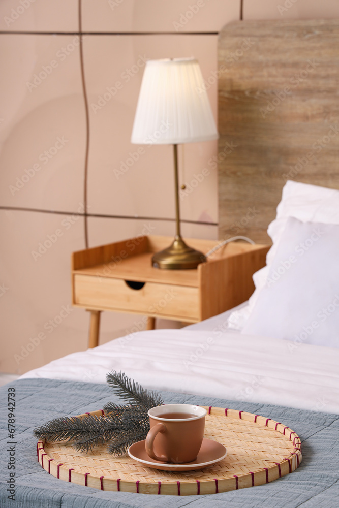 Cup of tea with fir branches on bed in room, closeup