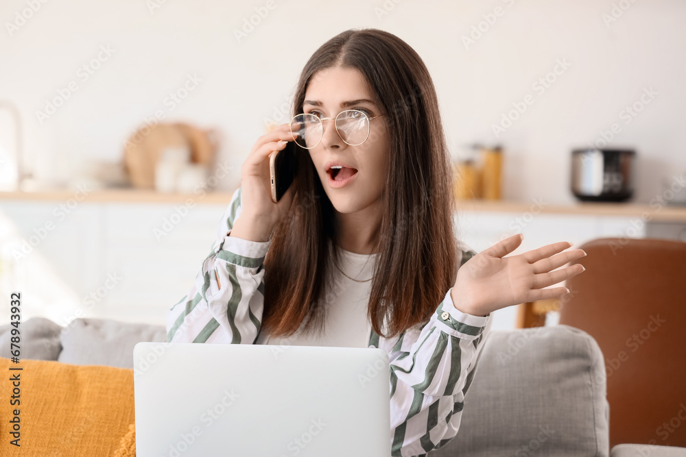 Young woman gossiping by mobile phone at home