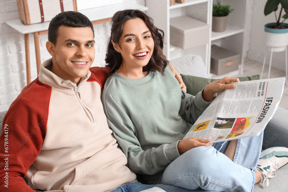 Young couple with newspaper at home