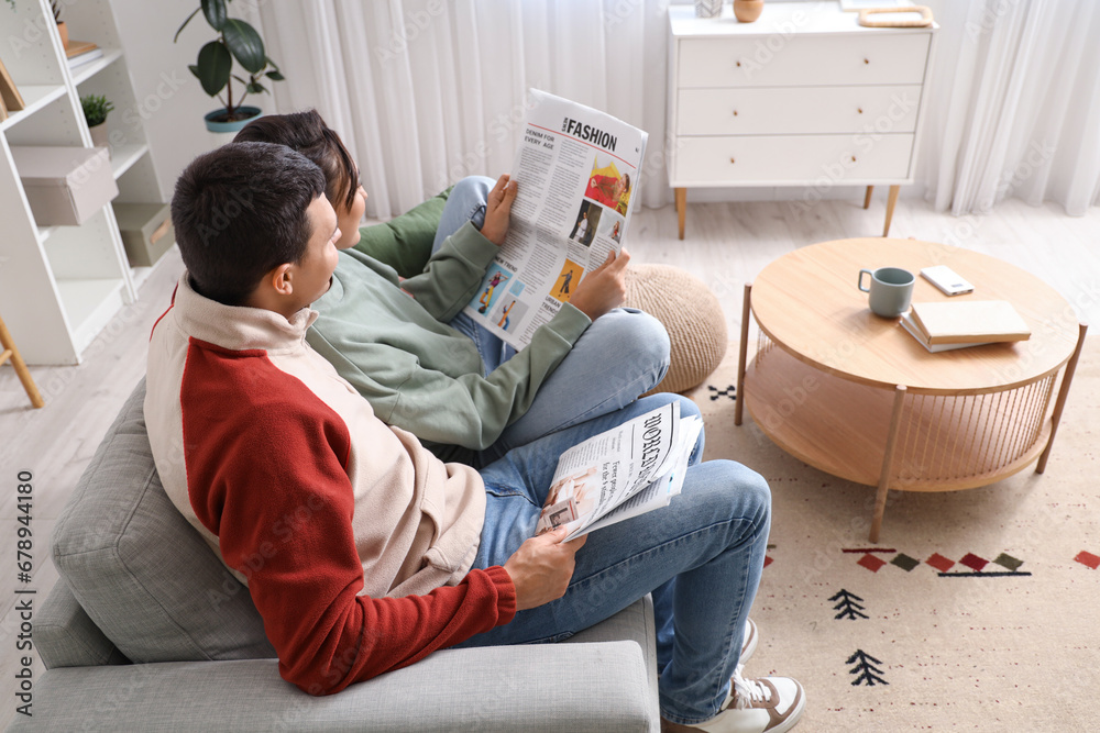 Young couple with newspapers at home