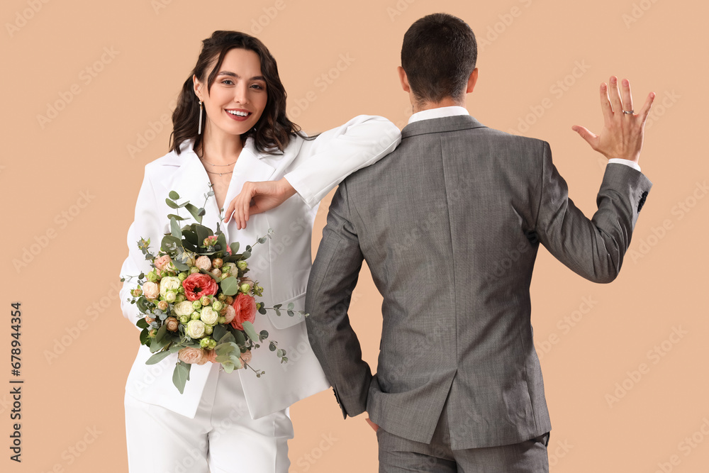 Young wedding couple with bouquet of flowers on beige background